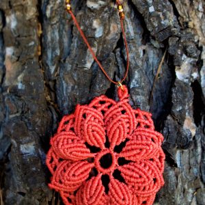 Χειροποίητο μακραμέ κολιέ σε σομόν χρώμα με λουλούδι στο κέντρο, τοποθετημένο σε ξύλινο φόντο