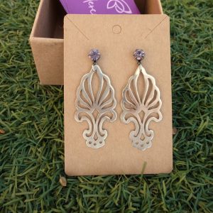 Χειροποίητα διάτρητα σκουλαρίκια από απλακά με κρυστάλλινη λεπτομέρεια, τοποθετημένα σε χάρτινη βάση μπροστά σε φυσικό φόντο.