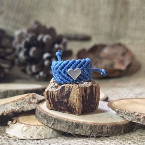 Μπλε μακραμέ δαχτυλίδι με ατσάλινη καρδιά επάνω σε ξύλινη βάση.