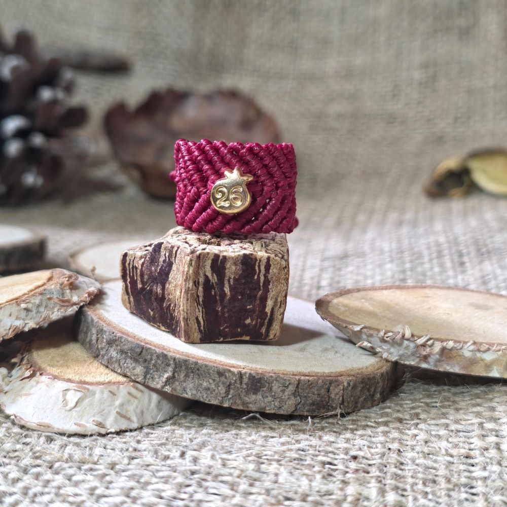 Μπορντό μακραμέ δαχτυλίδι με ατσάλινο ρόδι “26”, τοποθετημένο σε ξύλινη βάση.