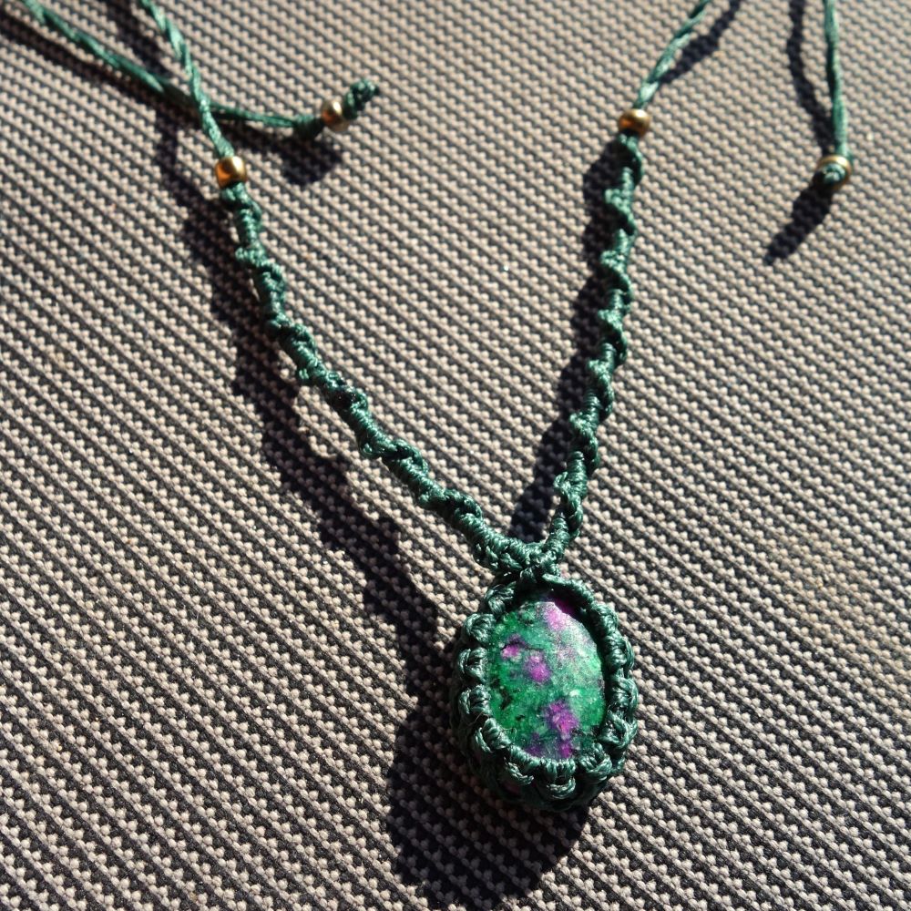 Πράσινο μακραμέ κολιέ με πέτρα Ρουμπίνι σε Ζοισίτη και χρυσές χάντρες σε γκρι φόντο.