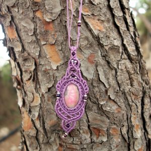 Μακραμέ κολιέ με ροζ ραγισμένο αχάτη σε μοβ πλέξη, φωτογραφημένο επάνω σε κορμό δέντρου.