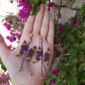 Μακραμέ σκουλαρίκια πεταλούδες σε μωβ και χρυσό με ατσάλινο γάντζο και μήκος 9 εκατοστά.