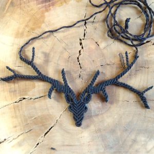 Καφέ μακραμέ κολιέ σε σχέδιο ελαφιού, τοποθετημένο επάνω σε ξύλινη επιφάνεια.