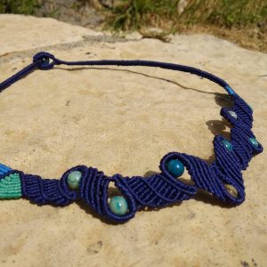 Μακραμέ κολιέ με navy πλέξη και πέτρες αχάτη light blue, τοποθετημένο επάνω σε πέτρινη επιφάνεια.