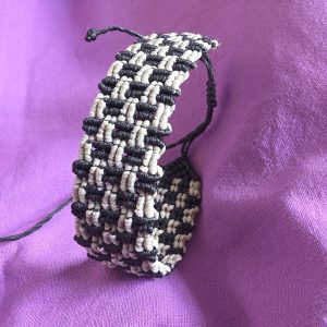 Χειροποίητο μακραμέ βραχιόλι Earthline σε μαύρο και μπεζ άμμου με αυξομείωση και λεπτομερή πλέξη