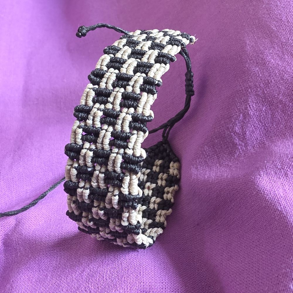 Χειροποίητο μακραμέ βραχιόλι Earthline σε μαύρο και μπεζ άμμου με αυξομείωση και λεπτομερή πλέξη