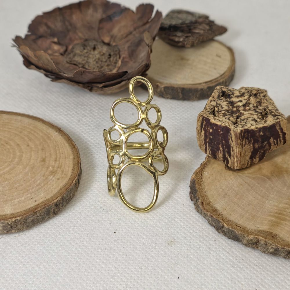 Χειροποίητο ορειχάλκινο δαχτυλίδι με οργανικό σχέδιο από κυκλικές φόρμες σε φυσικό φόντο ξύλου