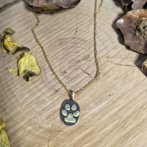 Χειροποίητο κολιέ από ορείχαλκο με πατίνα και σχέδιο πατούσας πάνω σε ξύλινη επιφάνεια με ατσαλινη αλυσίδα