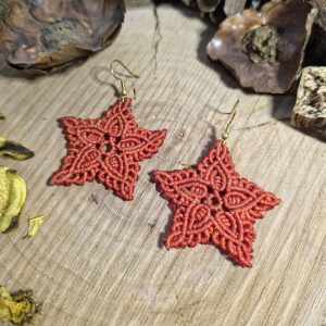 Χειροποίητα μακραμέ σκουλαρίκια σε σχήμα αστεριού, πορτοκαλί χρώμα, με ατσάλινα γαντζάκια πάνω σε ξύλινη επιφάνεια