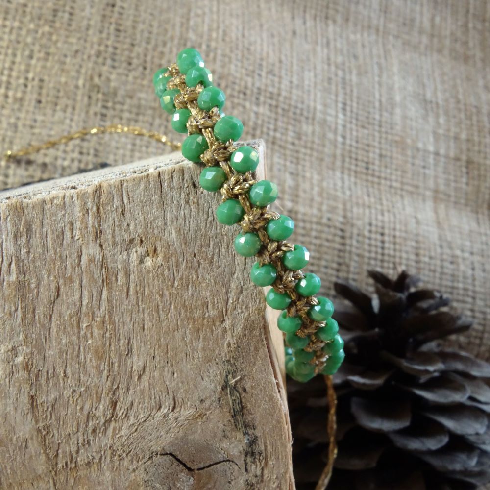 Χειροποίητο μακραμέ βραχιόλι με πράσινα κρυσταλλάκια και χρυσή κηροκλωστή σε φυσικό φόντο