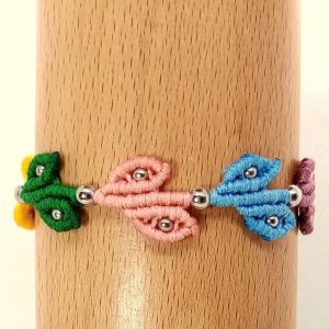 Χειροποίητο μακραμέ βραχιόλι με πολύχρωμα φυλλαράκια και μεταλλικές χάντρες πάνω σε ξύλινο φόντο